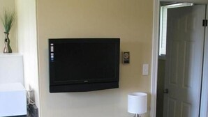 Een klein, donker bureau met een stoel en een televisie aan de muur.