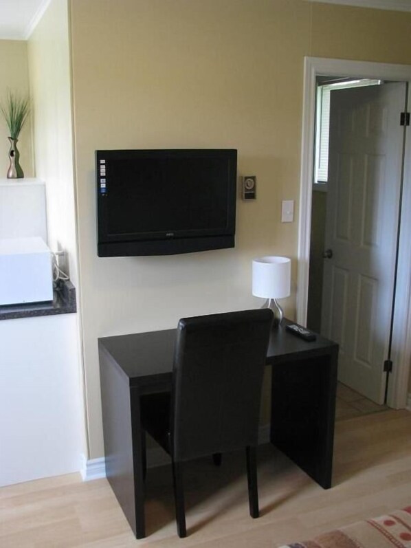 A small, dark-colored desk with a chair and a television mounted on the wall. - MacNeil's Motel  (Groves Point)