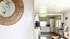 A modern kitchen with white cabinets, a wooden dining table, and a round mirror with a woven frame. - 7 Person Holiday Home in Hestra (Hestra)