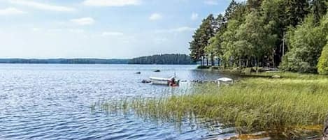 A lake with a dock and a boat, surrounded by trees and a clear sky.