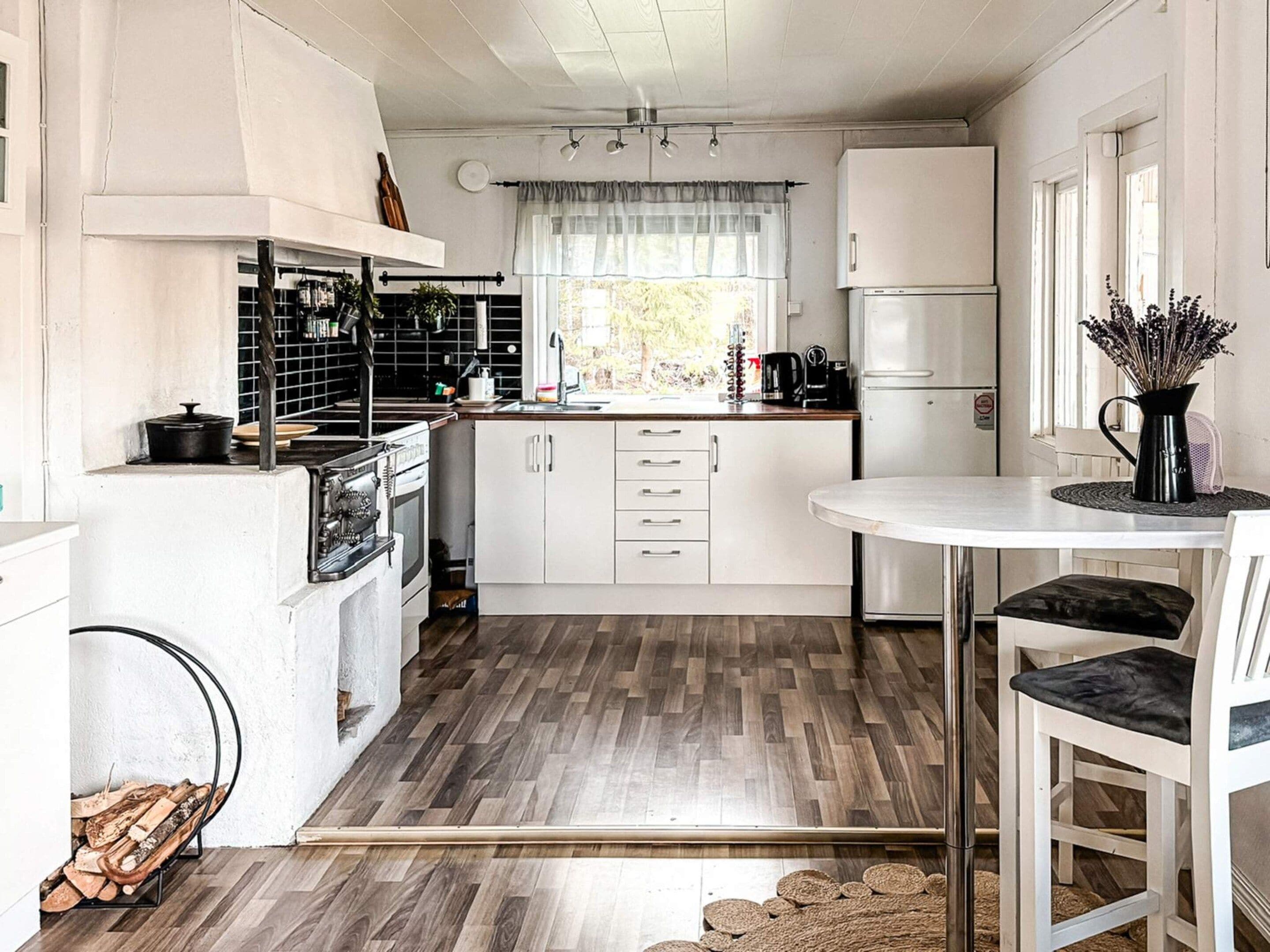A compact kitchen with white cabinets, a small dining area, and a window providing natural light.