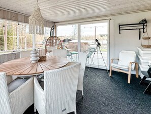 A room with a round wooden table, white wicker chairs, a hanging light fixture, and a telescope on a tripod. - 7 Person Holiday Home in Hestra (Hestra)