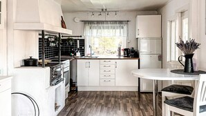 A compact kitchen with white cabinets, a stove, and a coffee maker. - 7 Person Holiday Home in Hestra (Hestra)