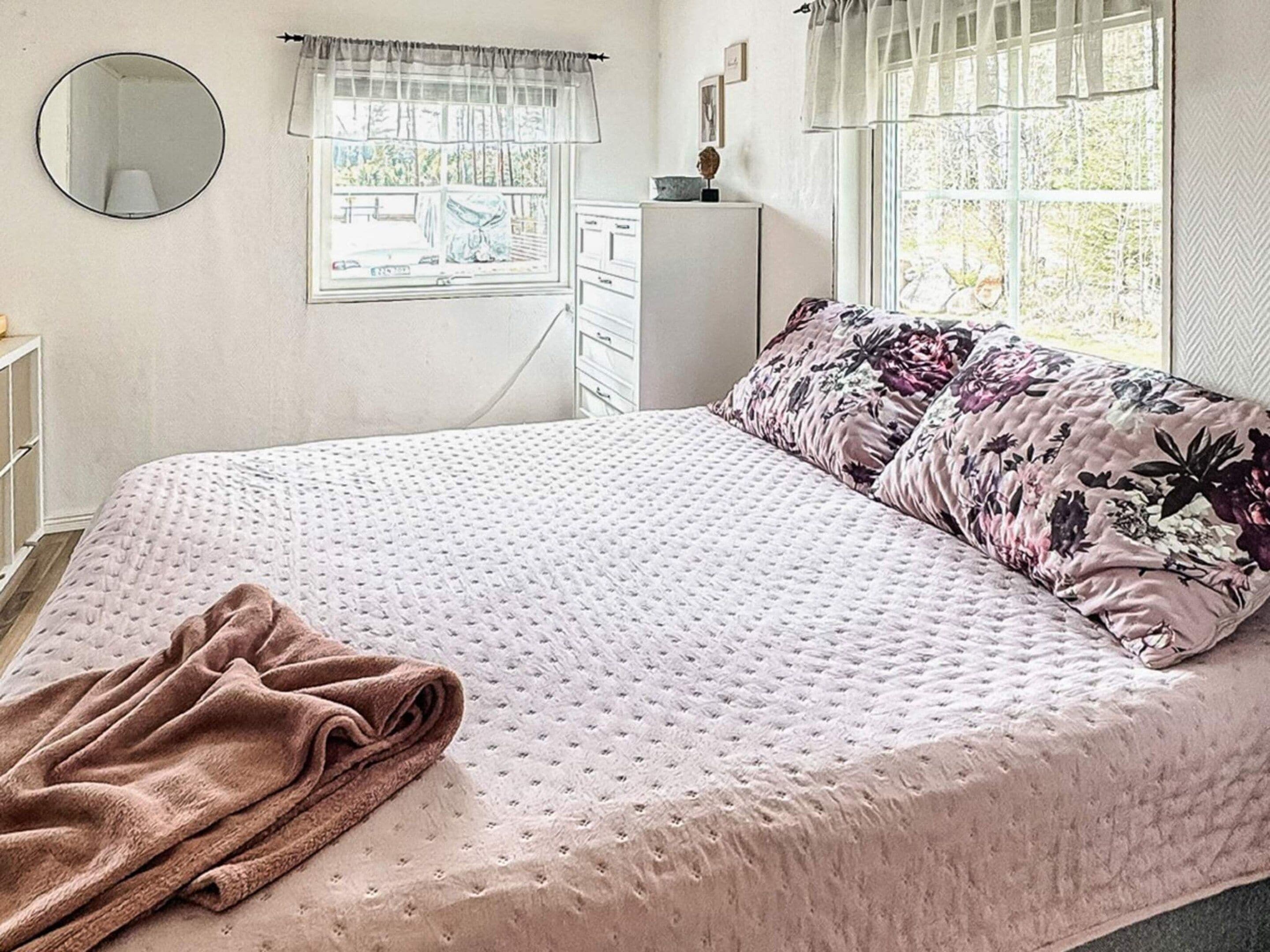 A bedroom with a bed, a window, a dresser, and a mirror.