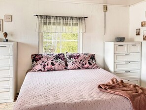 A bedroom with a bed, a window with curtains, a dresser, and a bedside table. - 7 Person Holiday Home in Hestra (Hestra)