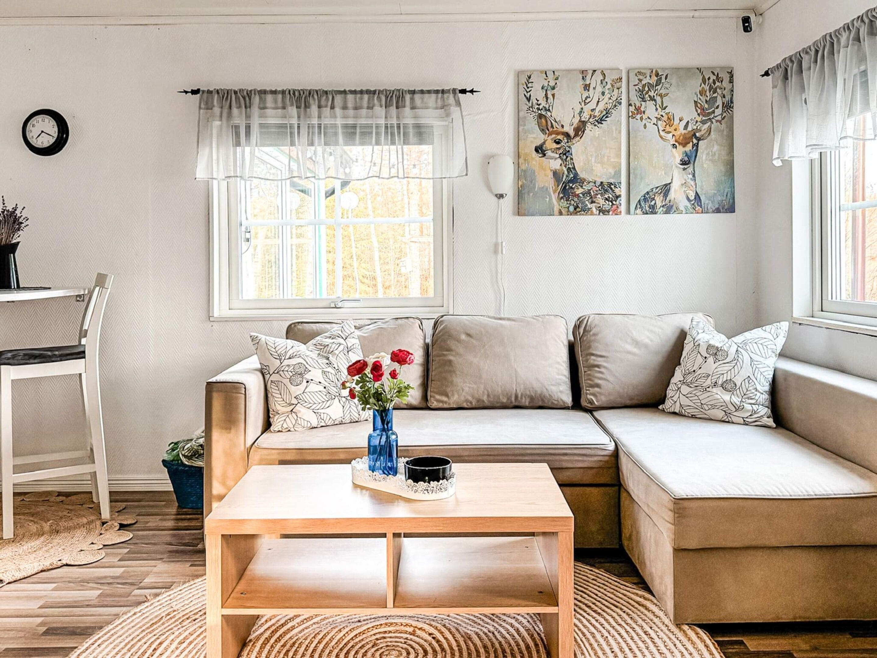A modern living room with a sofa, a coffee table, and a painting of deer.