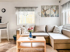 A modern living room with a sofa, a coffee table, and a painting of deer. - 7 Person Holiday Home in Hestra (Hestra)