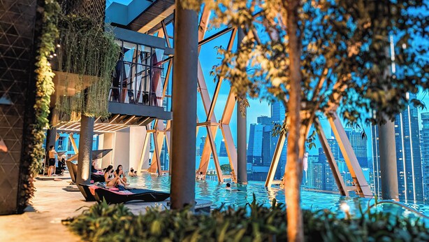 A modern pool area with a view of the city skyline, surrounded by greenery and architectural structures. - Scarletz Suites KLCC By Numa (Kuala Lumpur)