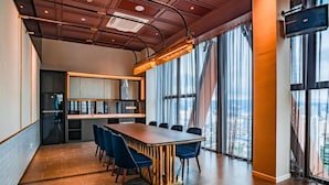 A modern conference room with a long table, blue chairs, a large window with a city view, and a unique ceiling design. - Scarletz Suites KLCC By Numa (Kuala Lumpur)
