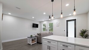 Una cocina moderna con armarios blancos, una isla grande e iluminación colgante.