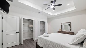 Un dormitorio con cama, ventilador de techo, armario y espejo.