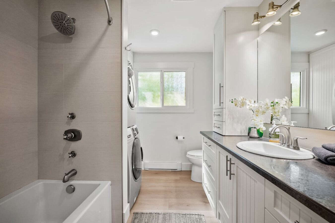 A modern bathroom with a bathtub, shower, toilet, and sink.