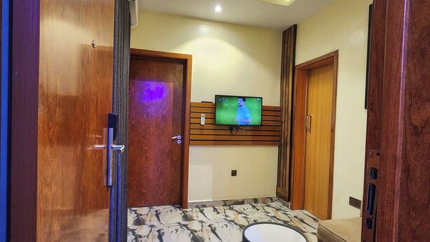 Una sala de estar moderna con suelo de mármol, un televisor montado en la pared y un sofá.