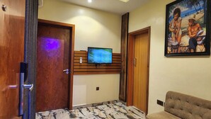 Una sala de estar con televisor, sofá, mesa de centro y un cuadro en la pared.