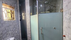 Un baño moderno con cabina de ducha de vidrio, inodoro y tocador con espejo.