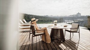 A person sitting at a round table with a view of a cityscape. - Porto D'Alma - Marques da Silva - T1 (Porto)