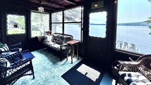 Una habitación acogedora con un gran ventanal con vistas a un lago, amueblada con sillas de mimbre y un sofá.