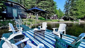 Un muelle con sillas Adirondack, una mesa y una sombrilla.