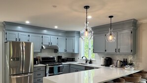 A modern kitchen with a large island, stainless steel appliances, and wooden bar stools. - Spacious, Family-Friendly Edgartown Home – 3BR, Sleeps 14, Renovated in 2025 (Edgartown)