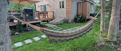 A house with a deck, a hammock, and a grill area.