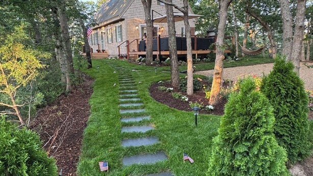 A stone pathway leading to a house surrounded by trees and well-maintained grass. - Spacious, Family-Friendly Edgartown Home – 3BR, Sleeps 14, Renovated in 2025 (Edgartown)