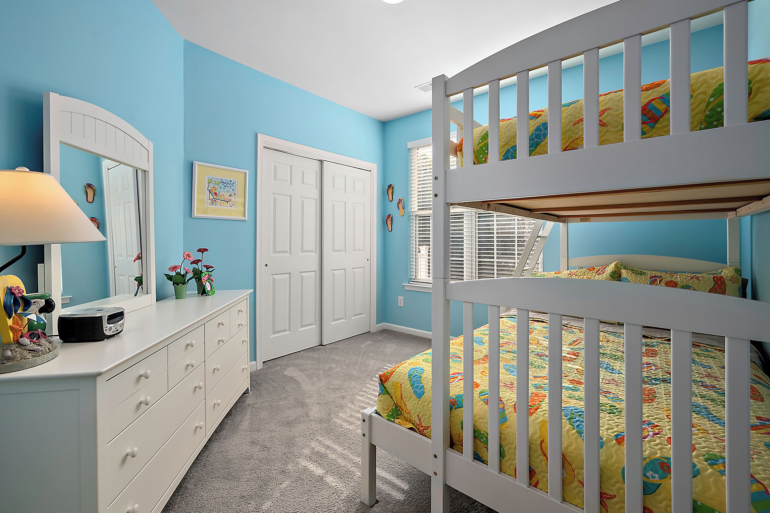 Un dormitorio con una cama litera, un aparador, un espejo y una puerta.