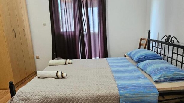 Un dormitorio con cama, armario y ventana con cortinas.