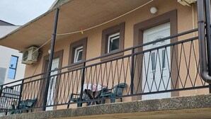 Un edificio con balcón, unidades de aire acondicionado y una ventana con cortina.