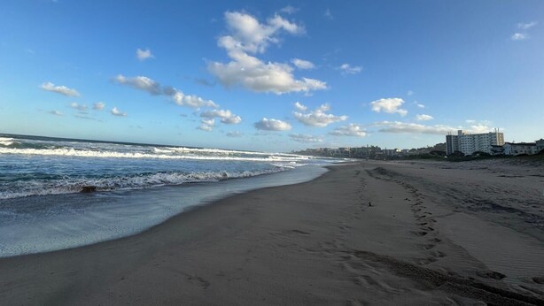 A beach with waves, a clear sky, and buildings in the background. - Suntide Cabanas ground floor studio apartment, Margate beach (Margate)