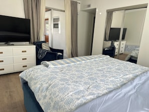 A hotel room with a bed, a TV, a desk, and a chair.