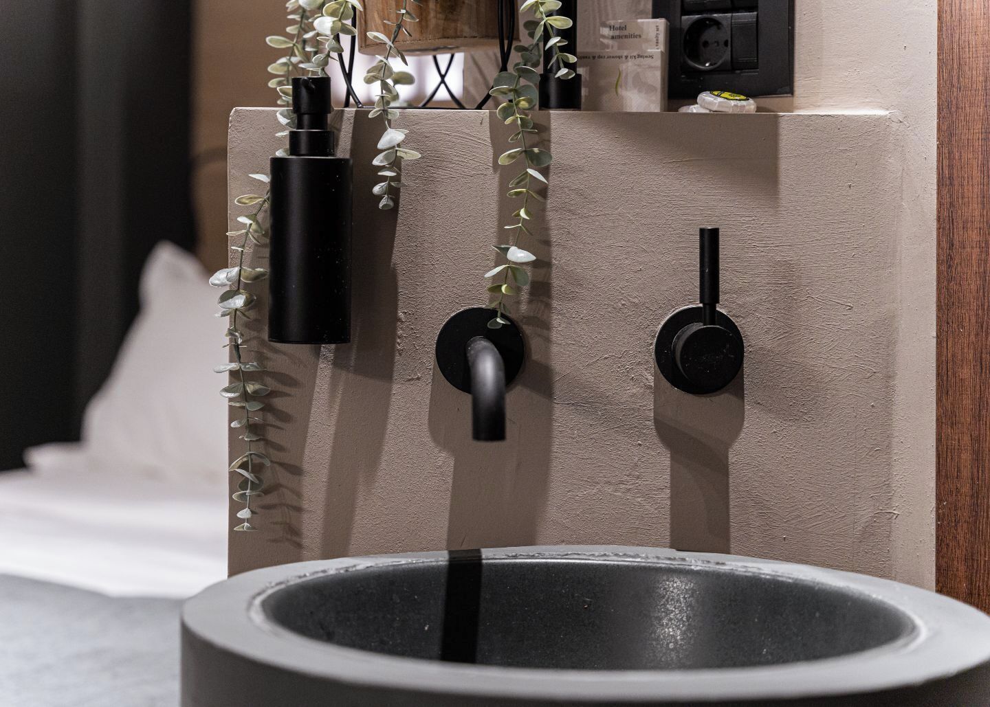 Un baño moderno con una bañera grande, un grifo negro y un perchero de pared con una planta.