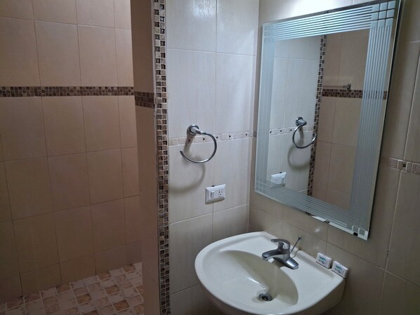 Un baño con lavamanos, espejo y barra de apoyo.