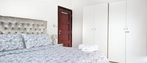 A bedroom with a bed, a wardrobe, and a door.