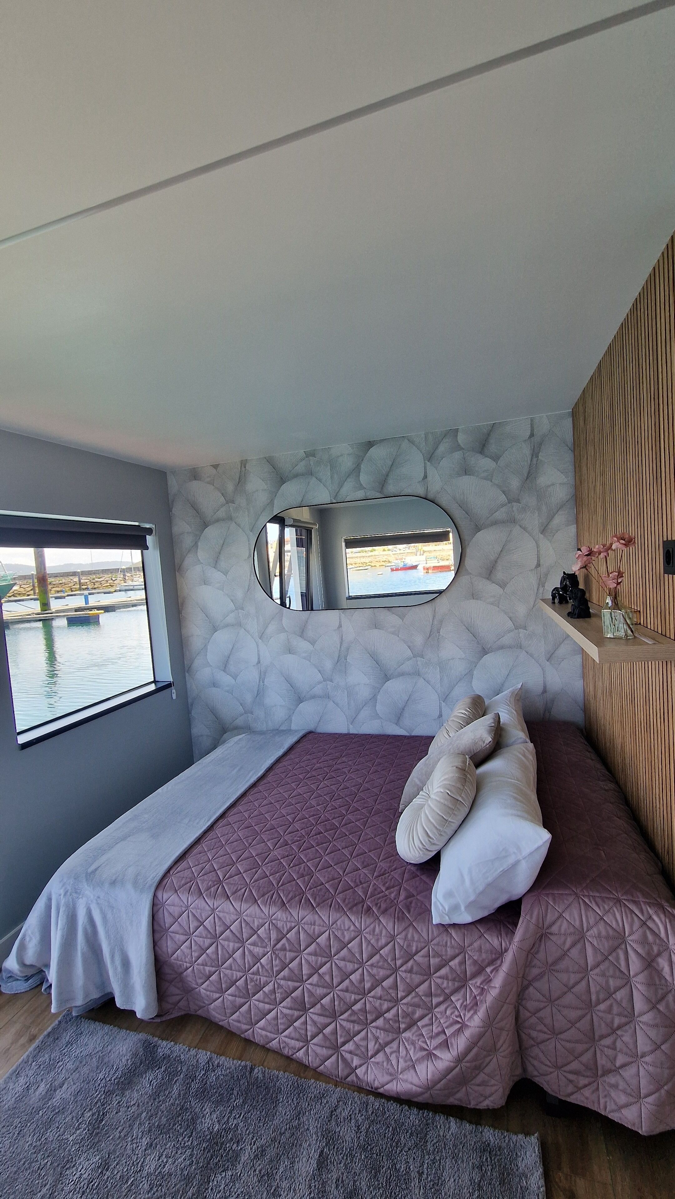 Une chambre à coucher avec un lit, une fenêtre, un miroir et une vue sur un quai.