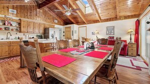 Comedor de madera con una mesa larga, sillas y un ventilador de techo.