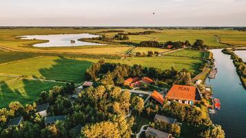 Vue aérienne d’une propriété rurale avec une rivière, des champs et un bâtiment portant l’inscription « PEAN » et surmonté d’un toit rouge.