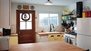 A kitchen with a wooden table, a sink, a stove, and cabinets.