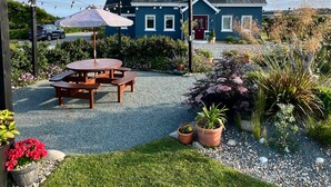 A blue house with a red door, a wooden table, and potted plants in the yard. - Thistledown Lodge (Templetown)