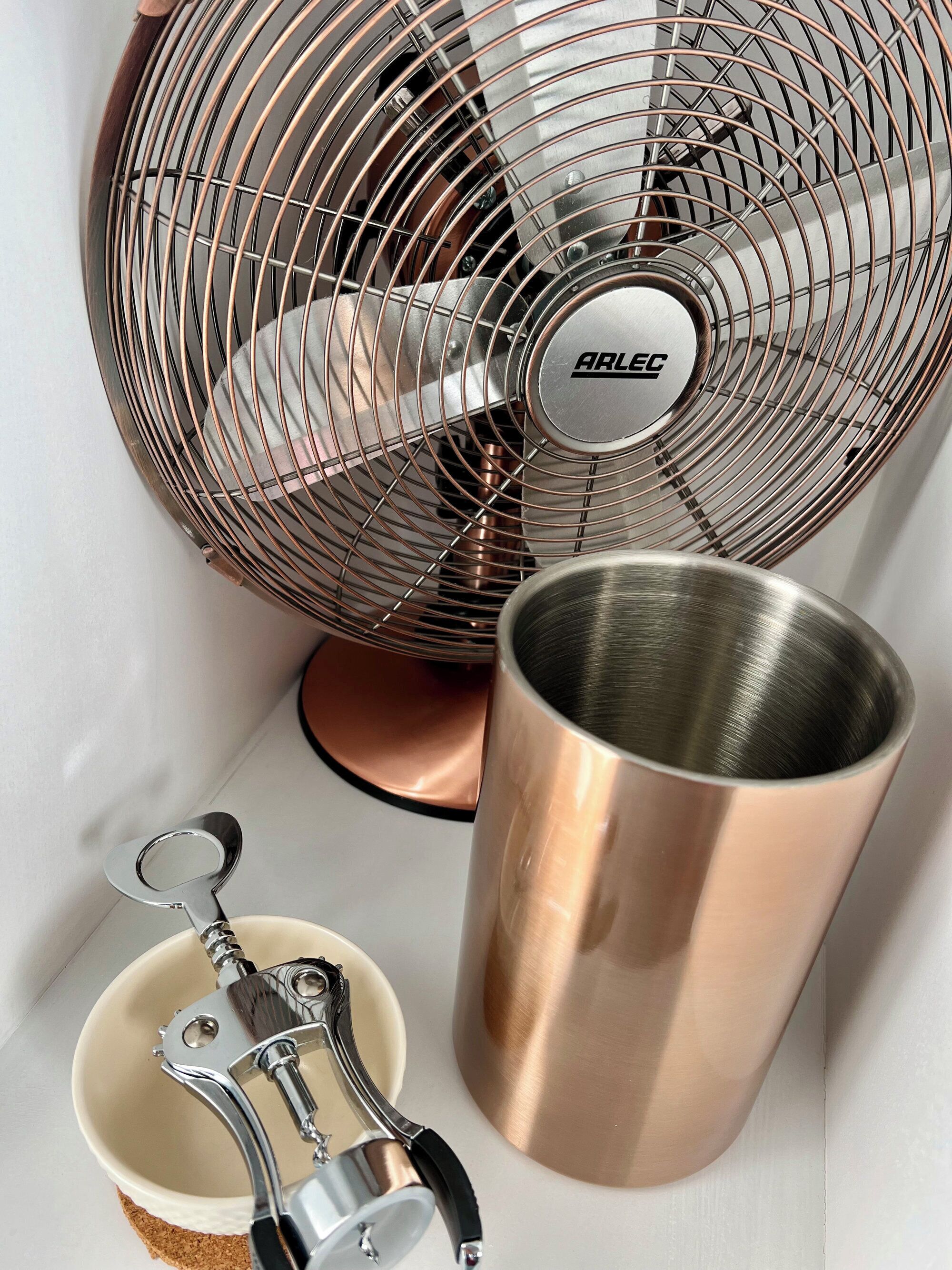 Angolo cottura con una ventola, un bicchiere d'acciaio inox e un porta utensili in metallo.