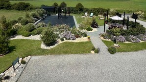 A landscaped area with a paved walkway, a black structure, and various plants and flowers. - Thistledown Lodge (Templetown)
