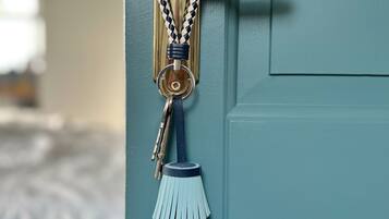A door with a brass handle and a keychain with a braided rope and a blue tassel.