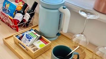 Una bandeja con una cafetera, una taza y una copa de vino sobre una mesa de madera.