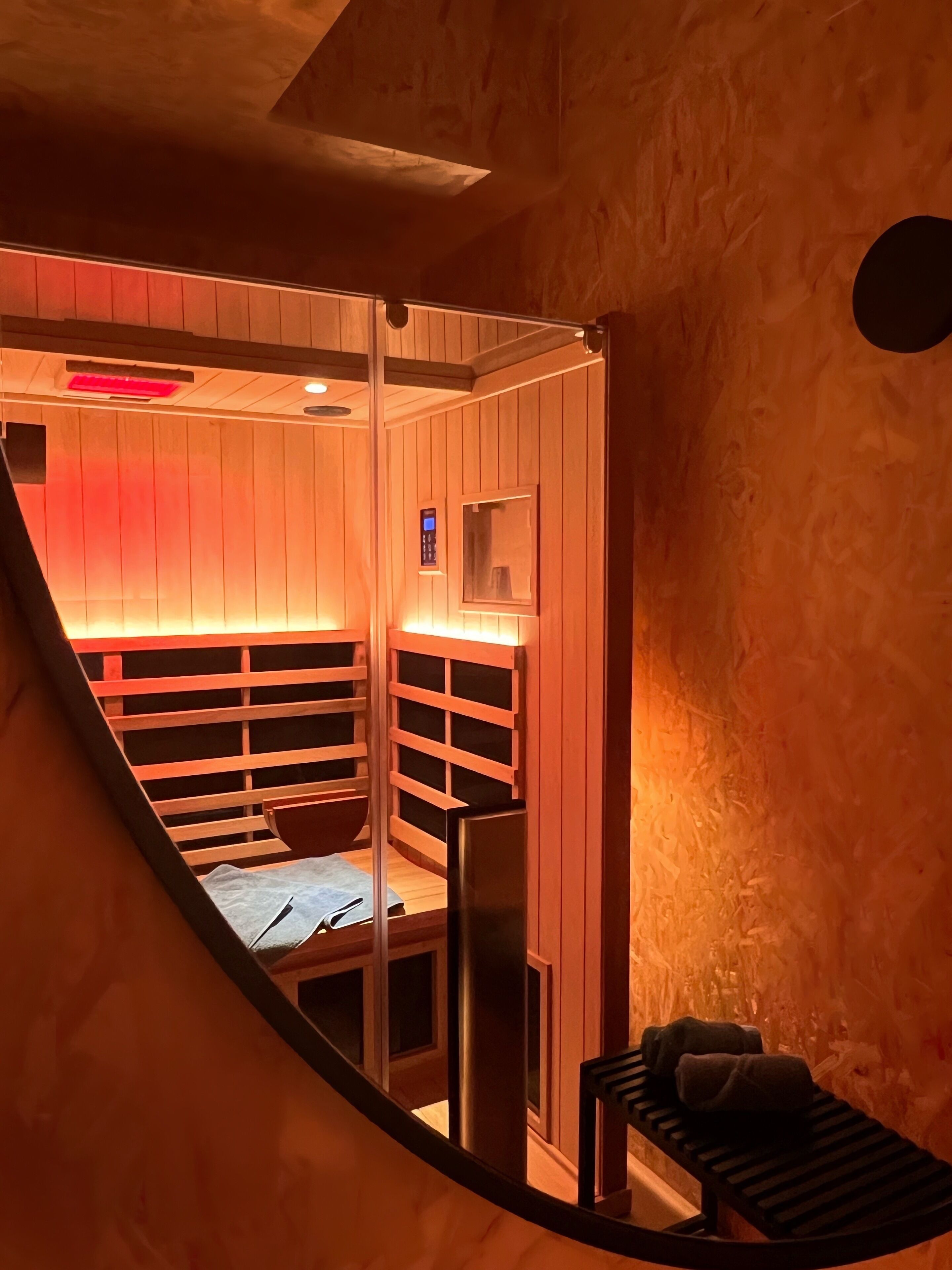 A sauna with wooden walls and a sloped ceiling, featuring a bench and towels.