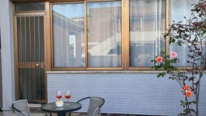 Un patio con una mesa y sillas, una ventana con vistas y una puerta con reja de metal.