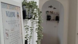 Un cartel de bienvenida con una lista de servicios y una planta en el pasillo.