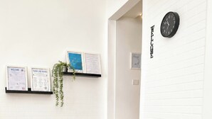 A black entertainment center with a flat-screen TV, a shelf with a plant, and a wall clock. - 2 minutes from the sea and all services. 9 minutes by car from the airport (Fiumicino)