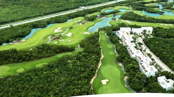 A golf course with bunkers, water hazards, and a clubhouse with multiple buildings.