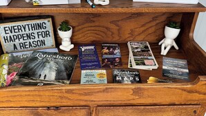A wooden cabinet with a 'Welcome Visitor Guest Book' and a 'Welcome to The Root River Trail House' sign. - Quaint home with large yard, pet friendly, bike storage right off the trailhead (Lanesboro)