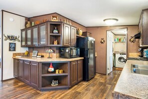 A compact kitchen with dark wood cabinets, a built-in microwave, and a refrigerator.
