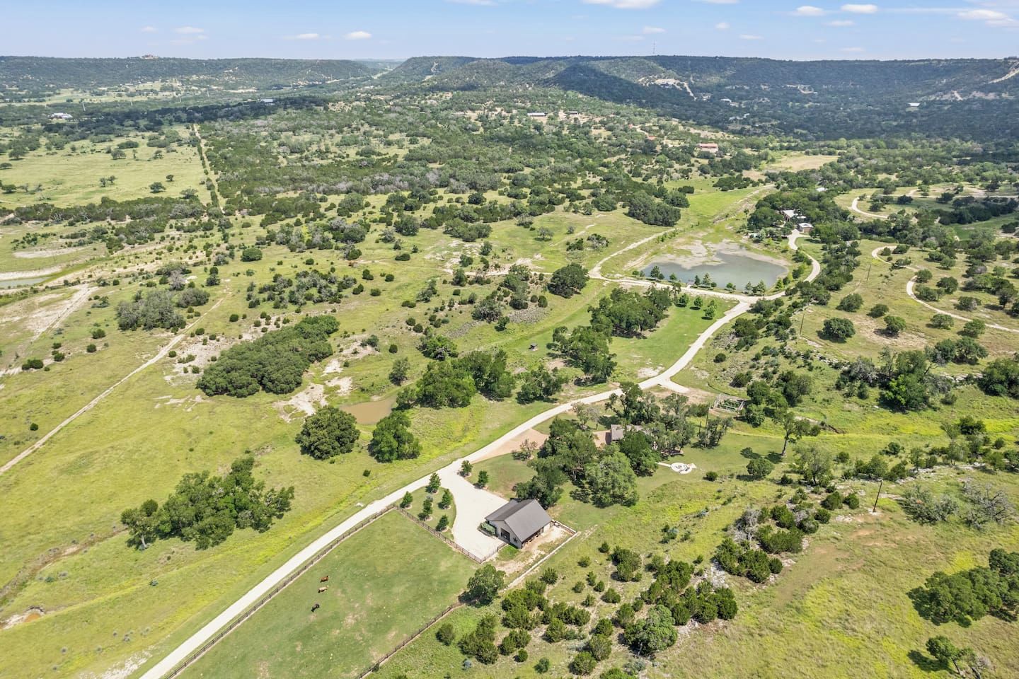 An aerial view of a rural landscape with scattered buildings, roads, and a large body of water.